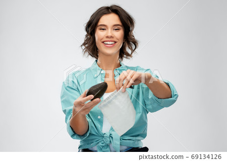 happy woman putting avocado into reusable bag happy woman putting avocado into reusable bag 69134126