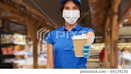 saleswoman in face mask with takeaway coffee cup saleswoman in face mask with takeaway coffee cup 69134230