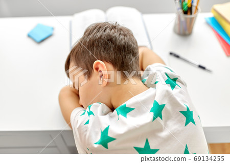 close up of tired boy sleeping on table at home close up of tired boy sleeping on table at home 69134255