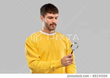 man in yellow sweatshirt with magnifier 69134304