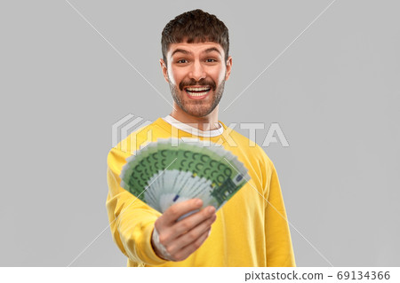 smiling young man in yellow sweatshirt with money smiling young man in yellow sweatshirt with money 69134366