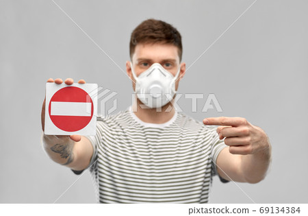 man in respirator mask showing stop sign man in respirator mask showing stop sign 69134384