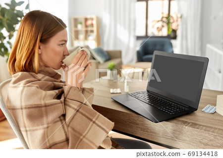 sick woman with tea having video call on laptop sick woman with tea having video call on laptop 69134418