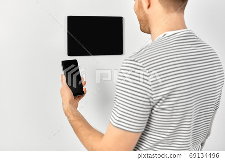man with smartphone and tablet pc at smart home man with smartphone and tablet pc at smart home 69134496