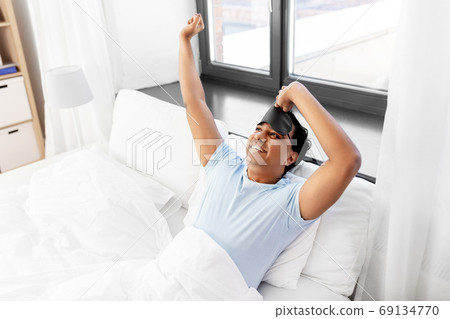 happy smiling indian man lying in bed at home happy smiling indian man lying in bed at home 69134770