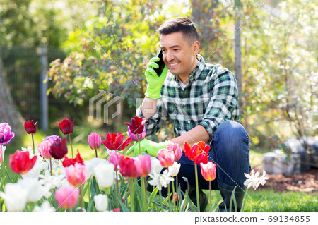 man with flowers calling on smartphone at garden 69134855