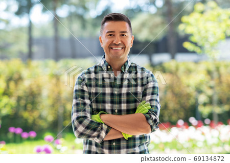 happy smiling middle-aged man in gloves at garden happy smiling middle-aged man in gloves at garden 69134872