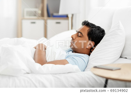 indian man sleeping in bed at home indian man sleeping in bed at home 69134902