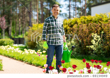 happy man with watering can and flowers at garden happy man with watering can and flowers at garden 69134949