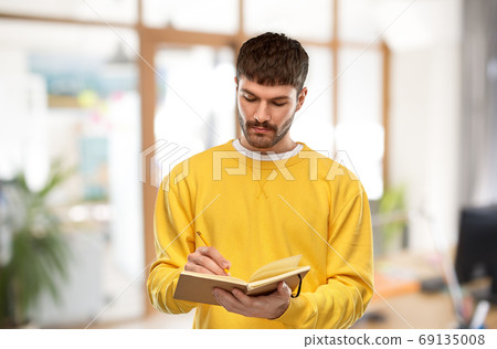 man in yellow sweatshirt writing to diary man in yellow sweatshirt writing to diary 69135008
