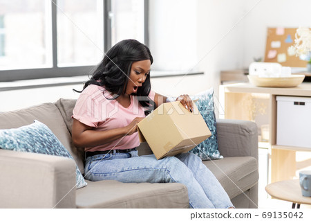african american woman opening parcel box at home african american woman opening parcel box at home 69135042