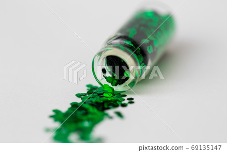 green glitters poured from small glass bottle 69135147
