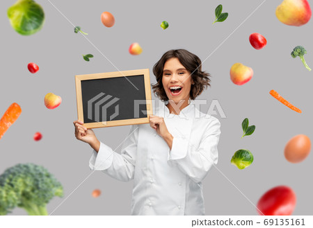 happy female chef holding chalkboard over food happy female chef holding chalkboard over food 69135161