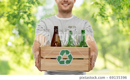 smiling young man sorting glass waste smiling young man sorting glass waste 69135396