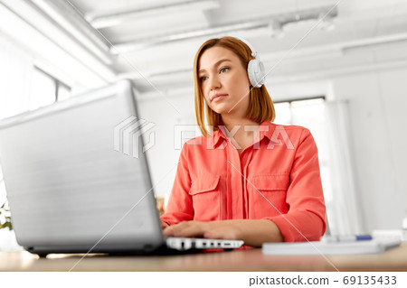 woman in headphones with laptop working at home woman in headphones with laptop working at home 69135433