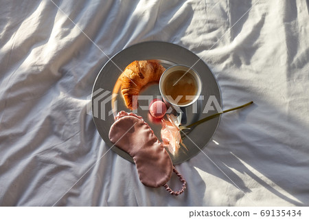 croissant, coffee and eye sleeping mask in bed croissant, coffee and eye sleeping mask in bed 69135434