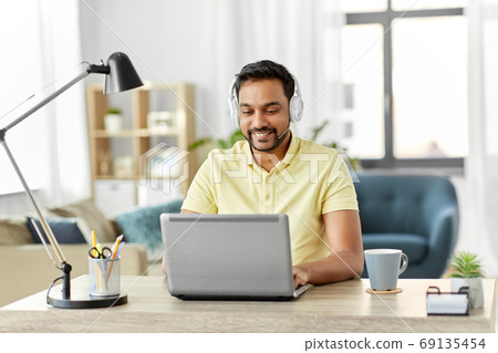 man in headphones with laptop working at home 69135454
