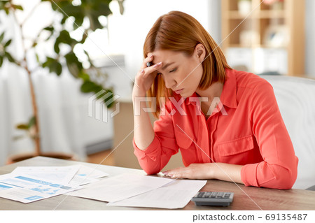 woman with calculator and papers working at home woman with calculator and papers working at home 69135487