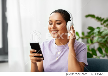 woman with smartphone listening to music at home woman with smartphone listening to music at home 69135658