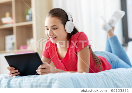girl in headphones listening to music on tablet pc girl in headphones listening to music on tablet pc 69135851