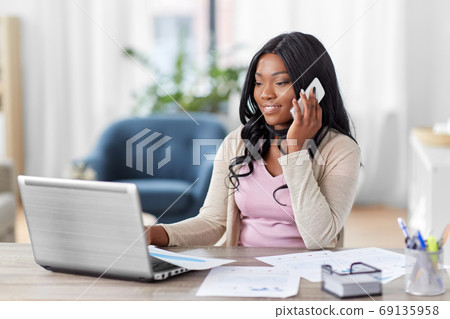 woman with laptop calling on phone at home office woman with laptop calling on phone at home office 69135958