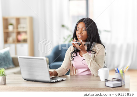 woman with laptop calling on phone at home office woman with laptop calling on phone at home office 69135959