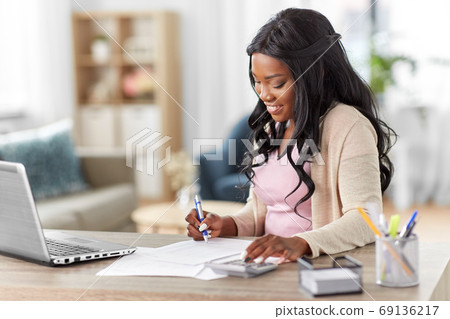 woman with calculator and papers working at home woman with calculator and papers working at home 69136217