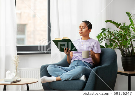 african american woman reading book at home 69136247
