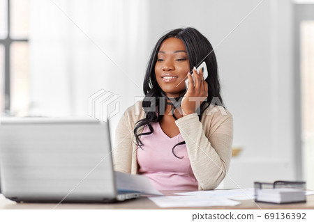 woman with laptop calling on phone at home office woman with laptop calling on phone at home office 69136392