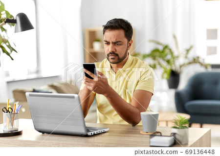 happy indian man with smartphone at home office happy indian man with smartphone at home office 69136448