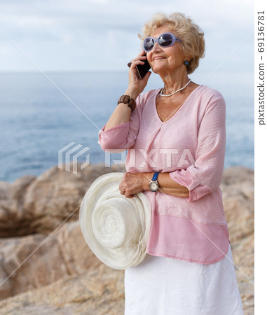 Aged woman talking on phone outdoors 69136781