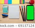 The top view of creative desk with office accessories, notebooks and colorful stickers. Wooden background with copy space for inscription. 69137124