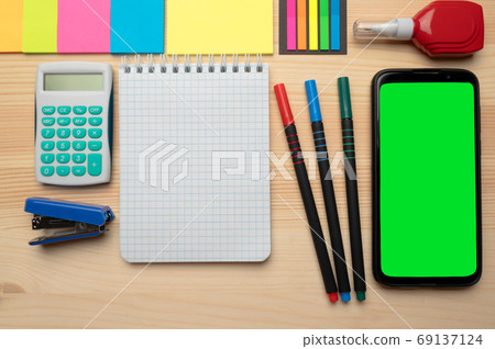 The top view of creative desk with office accessories, notebooks and colorful stickers. Wooden background with copy space for inscription. The top view of creative desk with office accessories, notebooks and colorful stickers. Wooden background with copy space for inscription. 69137124