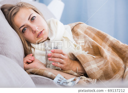 Young woman catching cold taking medication Young woman catching cold taking medication 69137212