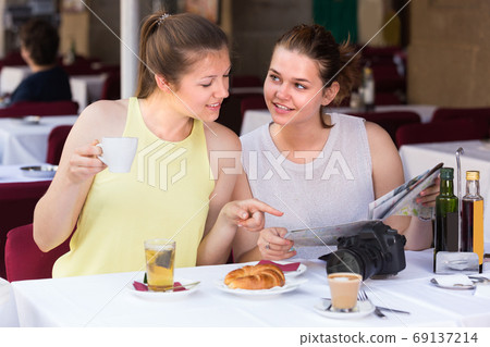 Portrait of young female tourists with map which are sitting and talking in cafe 69137214