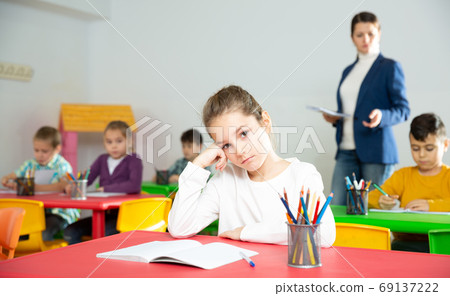 Tired schoolgirl at pupils desk at lesson Tired schoolgirl at pupils desk at lesson 69137222