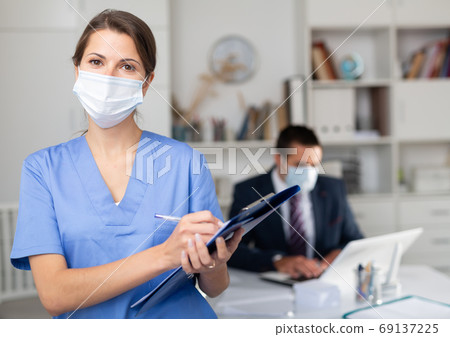 Female medical worker meeting staff in office, monitoring health status Female medical worker meeting staff in office, monitoring health status 69137225