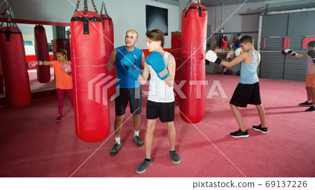 Sportsman at boxing workout on punching bag Sportsman at boxing workout on punching bag 69137226