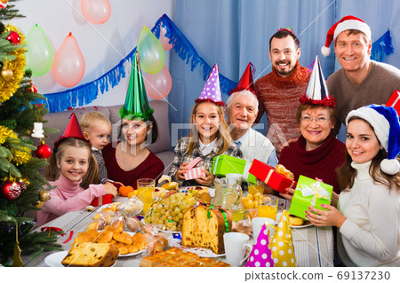Large family exchanging gifts during Christmas dinner Large family exchanging gifts during Christmas dinner 69137230