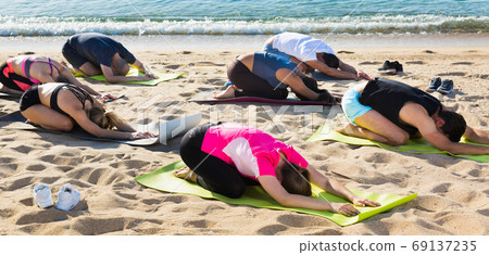 People practicing yoga on beach People practicing yoga on beach 69137235