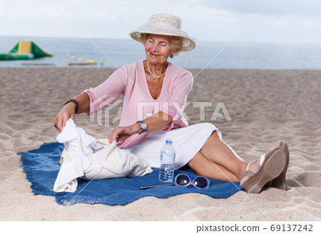 Elderly woman relaxing on beach Elderly woman relaxing on beach 69137242