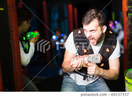 Excited guy during lasertag game Excited guy during lasertag game 69137337