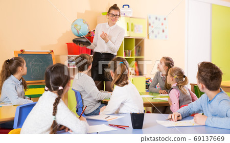 group of pupil with teacher sitting at table and studying group of pupil with teacher sitting at table and studying 69137669