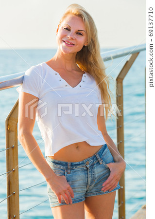 Cheerful female is posing playfully on pirce in her free time Cheerful female is posing playfully on pirce in her free time 69137710