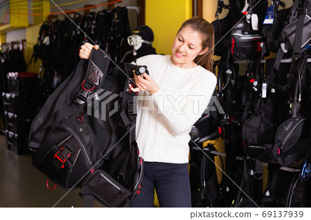 Sporty woman is satisfied of new diving vest in the diving store. Sporty woman is satisfied of new diving vest in the diving store. 69137939