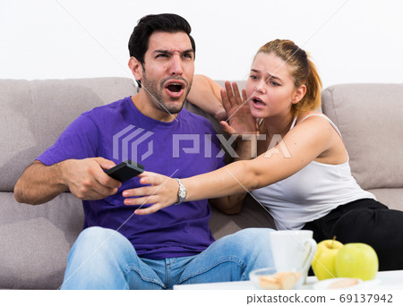 Couple on sofa quarreling because of TV remote 69137942