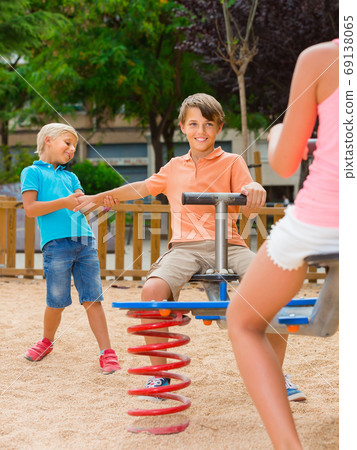 children are teetering on the swing in the playground. children are teetering on the swing in the playground. 69138065