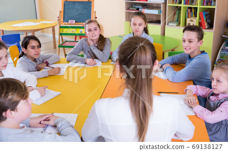 Smiling pupils with teacher sitting at table in class Smiling pupils with teacher sitting at table in class 69138127