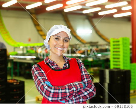 Portrait of positive female worker in uniform with arms crossed standing in warehouse Portrait of positive female worker in uniform with arms crossed standing in warehouse 69138166