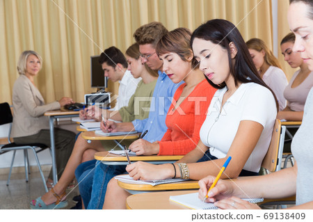 Side view of student group with female teacher on lecture 69138409